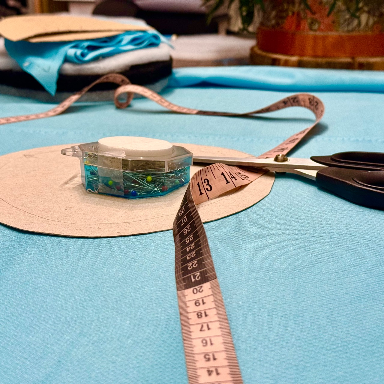 Scissors, pins and a tape measure on blue fabric while making the custom fur for the spcmic.